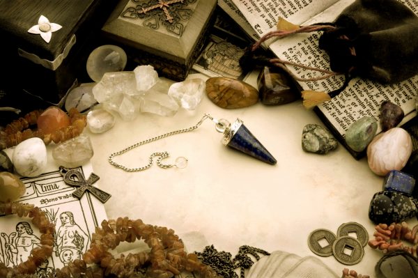 Witchcraft Supplies including crystals, trinket boxes and a spell book all laid out on a surface